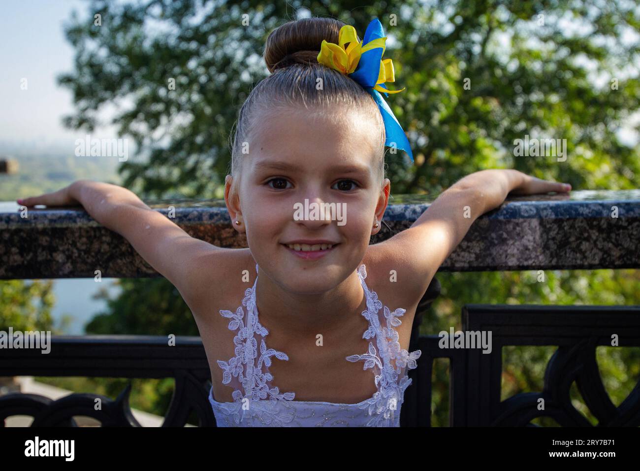 KIEW, UKRAINE - 29. SEPTEMBER 2023 - Ein Mädchen in einem Ballkleid mit blauen und gelben Bändern im Haar wird vor der Zeremonie zur Verleihung der Schulter abgebildet Stockfoto