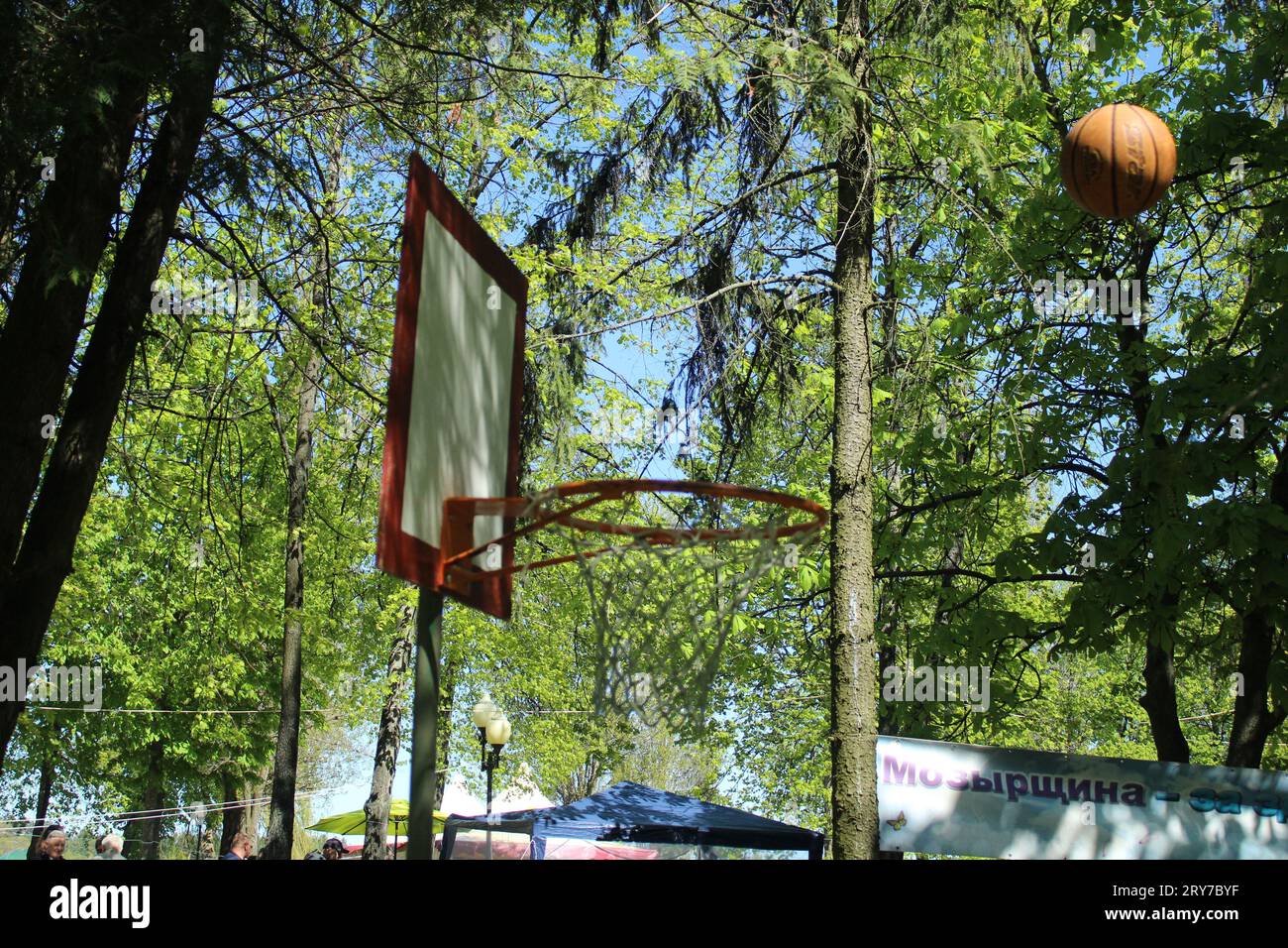 Straßenballspiele, Basketball auf der Straße, den Ball mit einem Netz in einen Reifen werfen. Sportspiele. Anfänger, körperliche Aktivität. Stockfoto