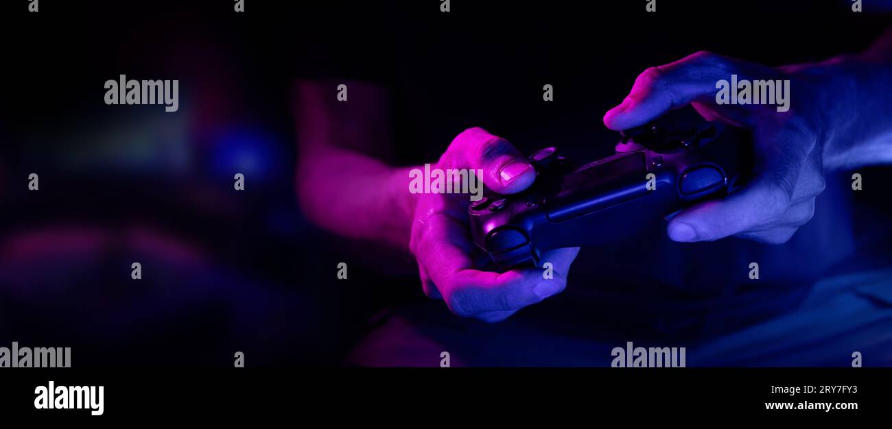Nahaufnahme des kabellosen Videospielcontrollers in den Händen des Spielers in Neonlicht. Banner mit Kopierraum Stockfoto