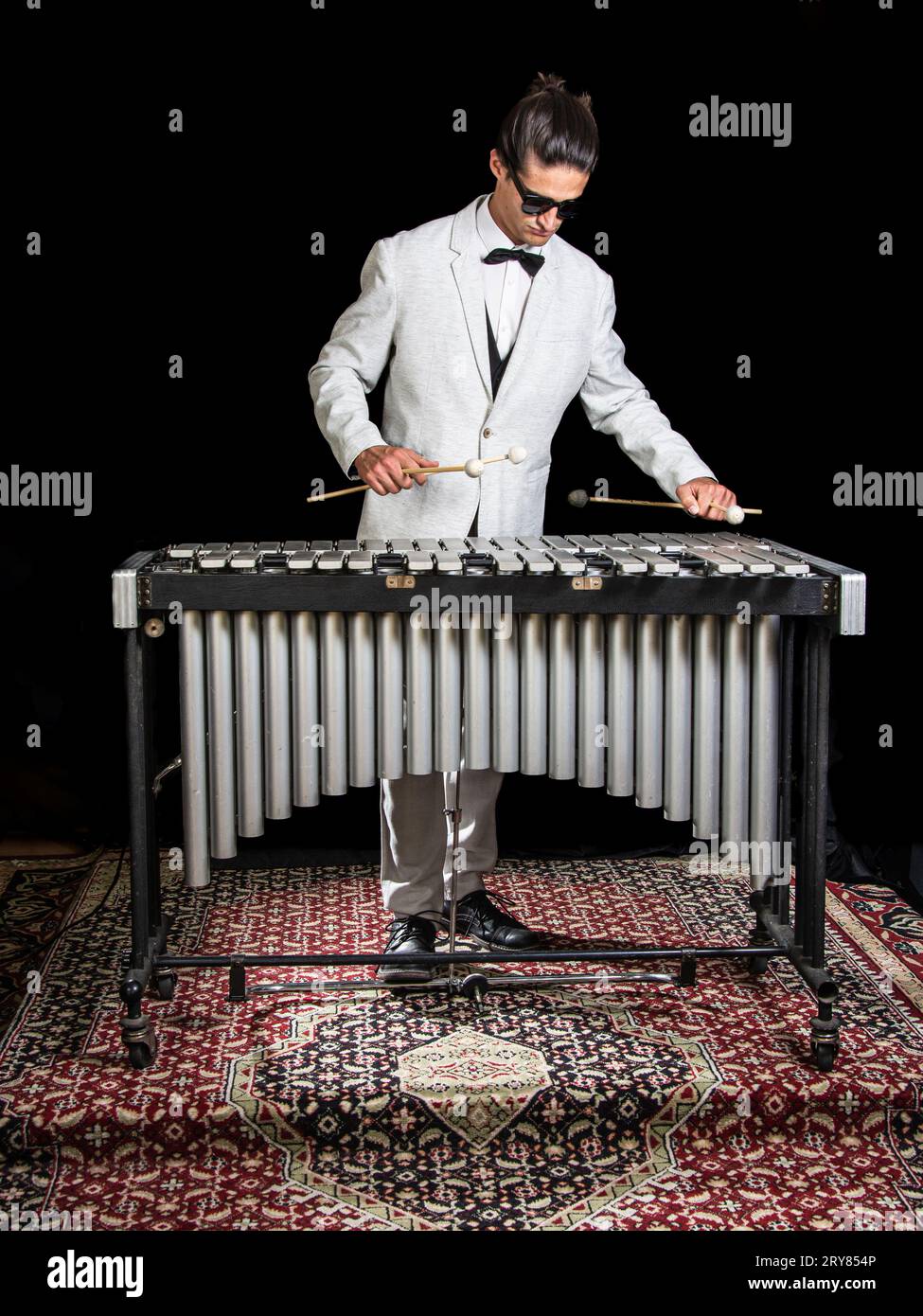 Junger Jazzmusiker spielt das Vibraphone in seinem privaten Proberaum. Schwarzer Hintergrund. Stockfoto