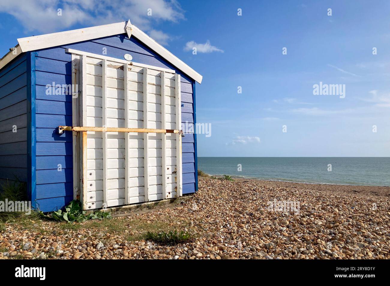Blaue Strandhütte mit weißer Tür steht vor blauem Himmel und Meer am Strand. Southampton, Vereinigtes Königreich, England Stockfoto