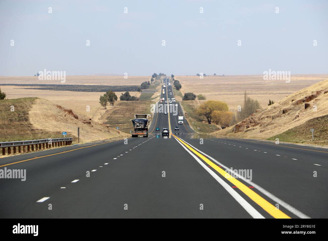 Die Autobahn N3 zwischen Durban und Johannesburg aus Sicht der Fahrer, die Autobahn bis zum Horizont mit Autos und Lkws und trockener Landschaft Stockfoto
