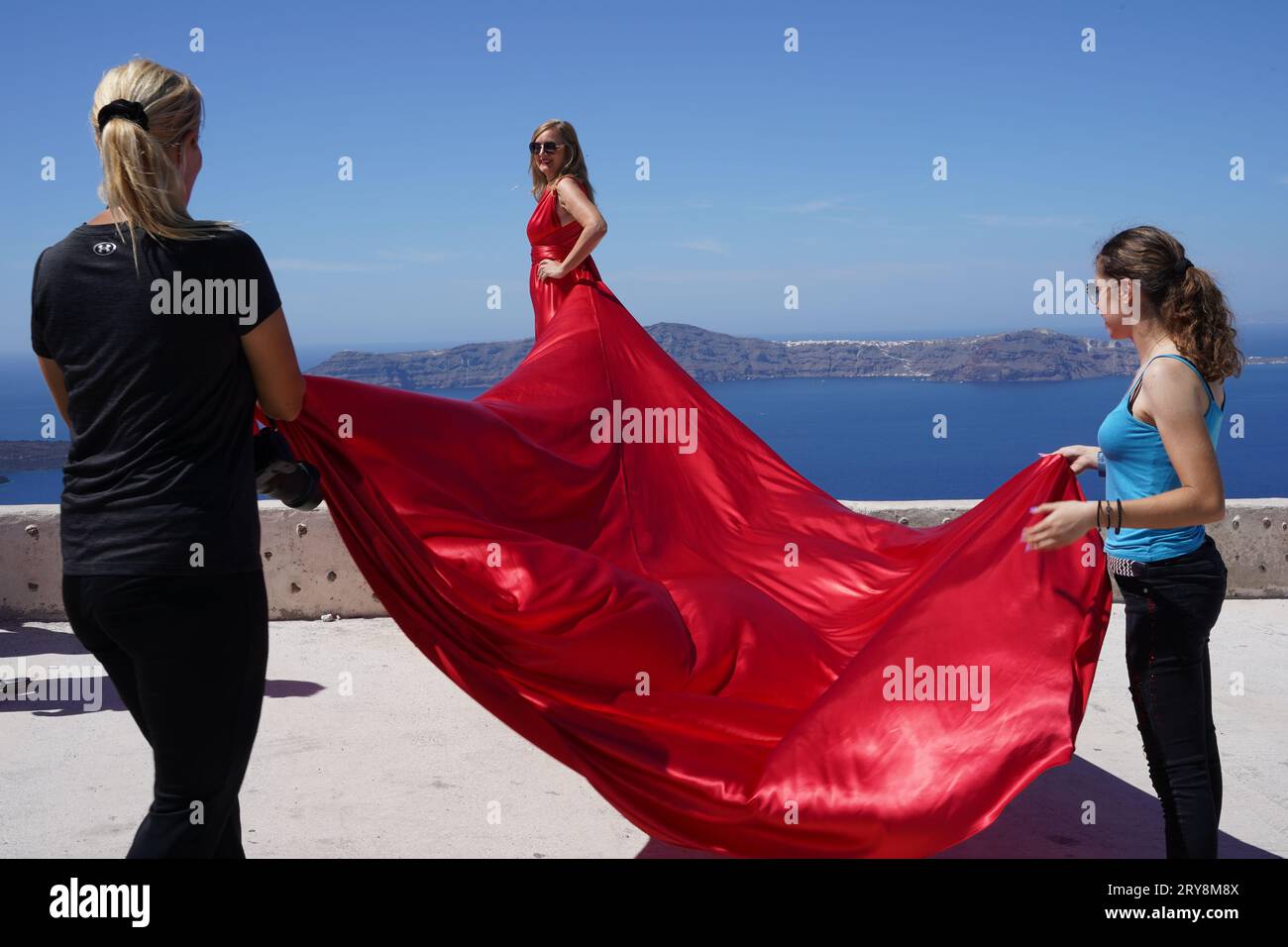 Zwei Assistenten halten den Zug des Models in einem roten Kleid. Stockfoto