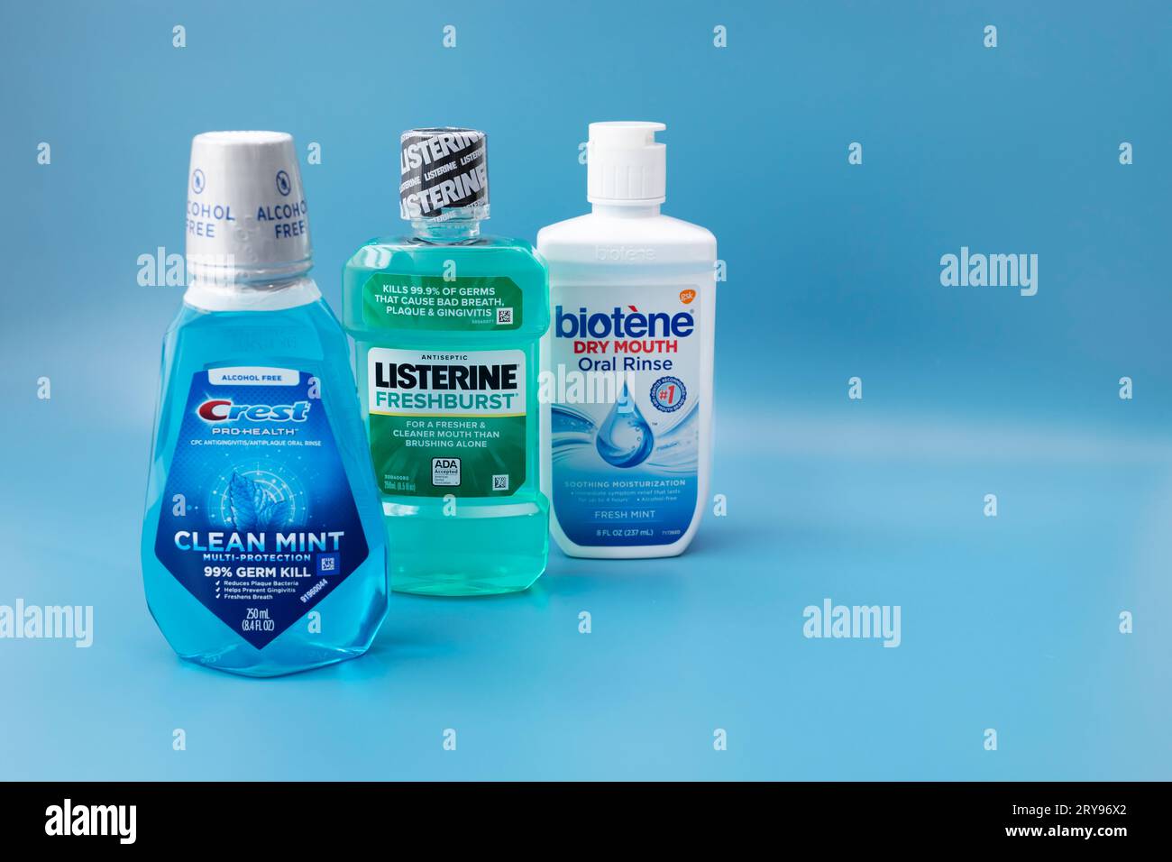 Einige Mundspül- oder Mundspülflaschen „Crest“, „Listerine“, „Biotene“ auf blauem Hintergrund. Platz Für Text. Flüssigkeit zum Spülen des Mundes. Oralcare-Produkt Stockfoto