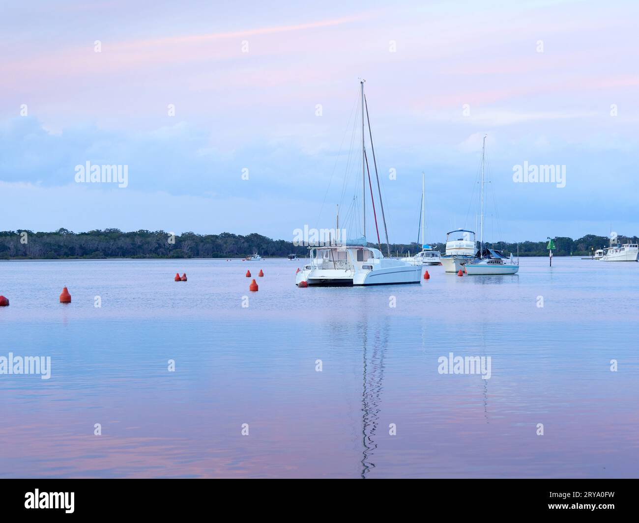 Tin Can Bay Queensland Australien mit einem umgekehrten Sonnenuntergang über der Bucht und verankerten Booten. Stockfoto