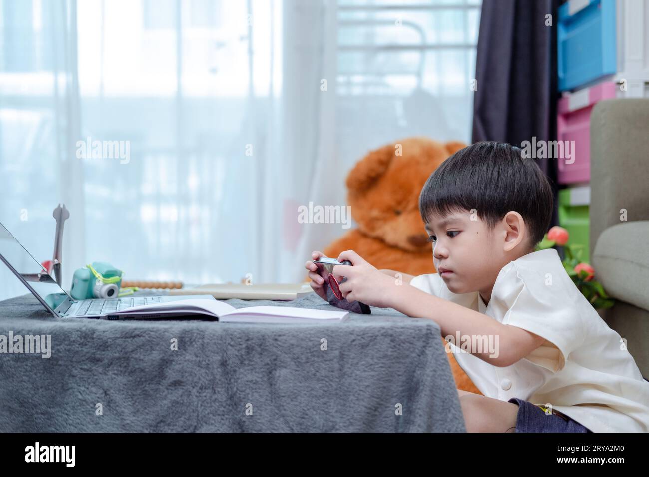 Asiatischer Junge, der online auf dem Handy lernt Stockfoto