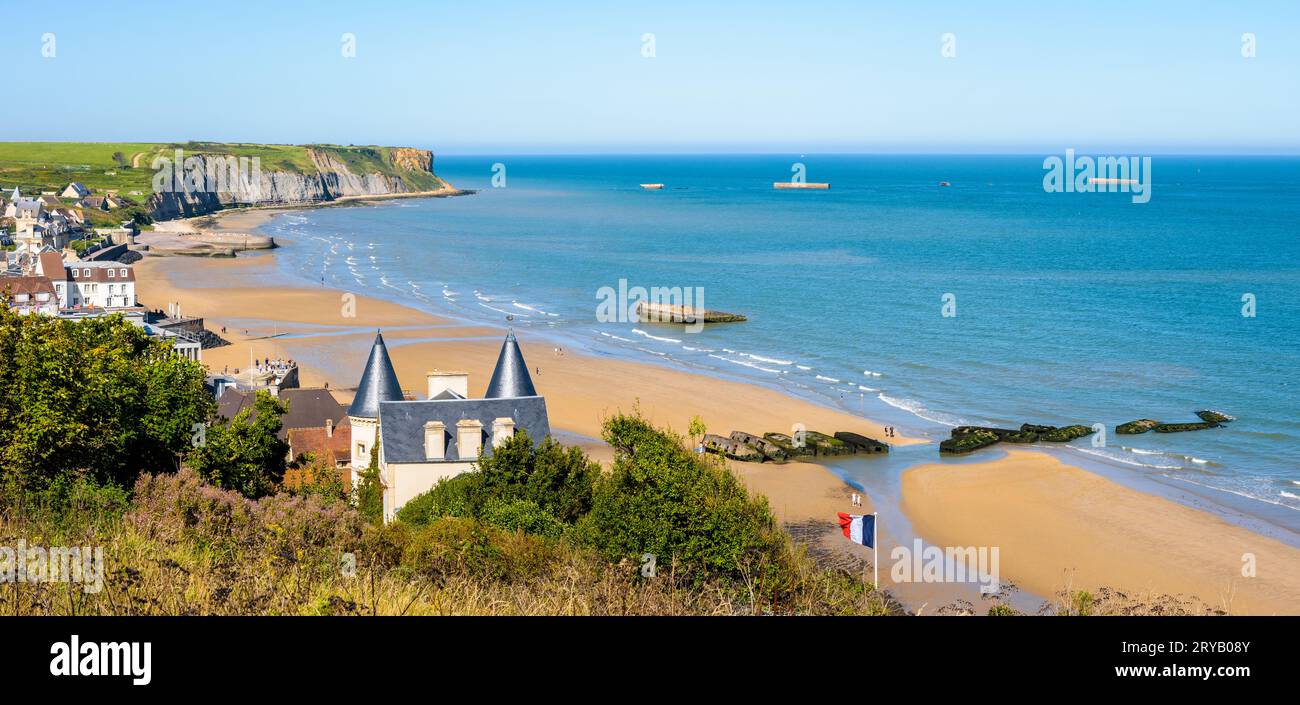 Blick auf den Strand von Arromanches in der Normandie an einem sonnigen Tag mit Überresten des Mulberry-Hafens aus dem Zweiten Weltkrieg auf dem Sand und den Phoenix Caissons im Meer Stockfoto