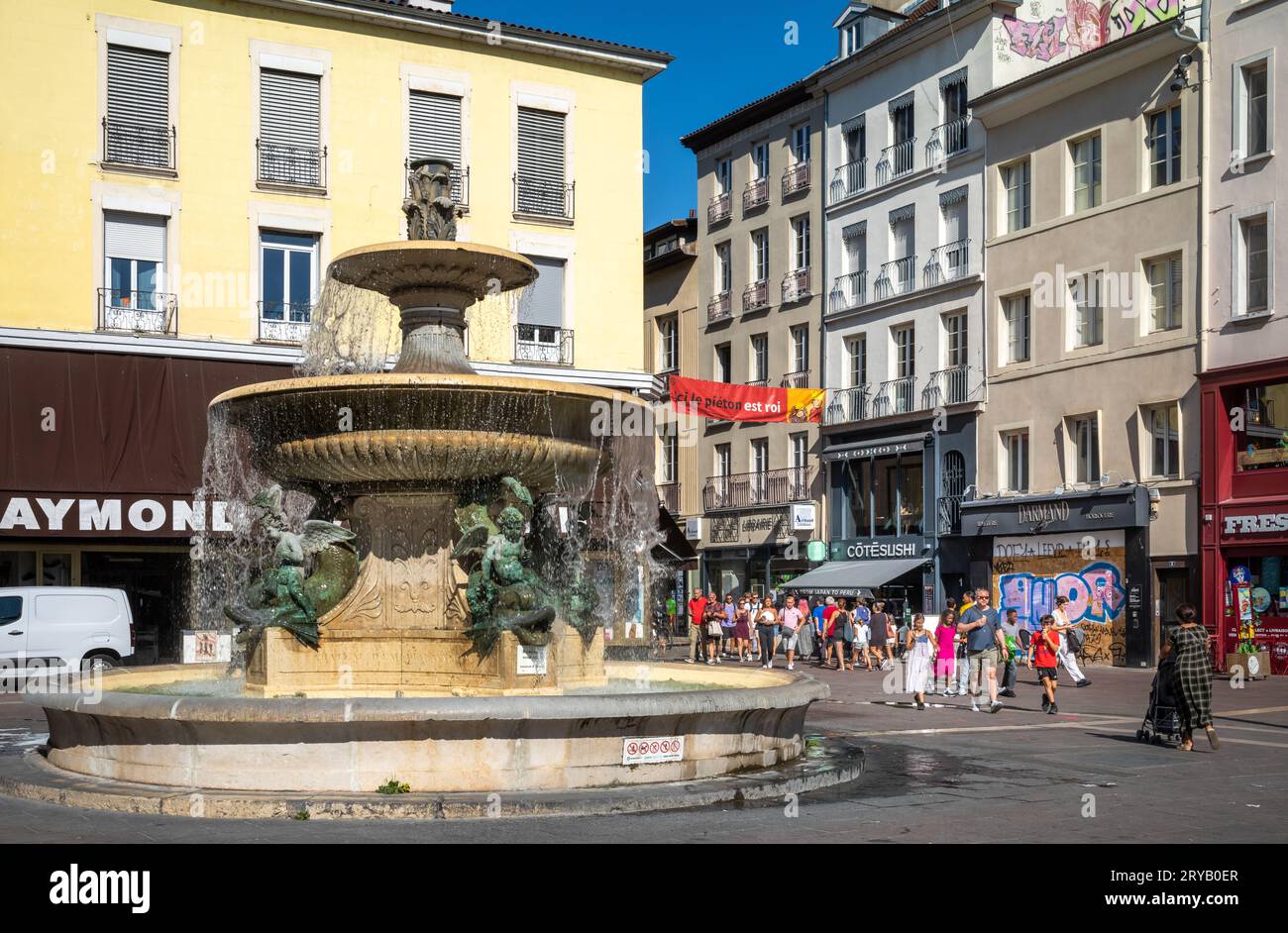 An einem sonnigen Samstagnachmittag schlendern die Leute an Geschäften und dem Lavalette-Brunnen in Place Grenette im Zentrum von Grenoble, Frankreich. Stockfoto