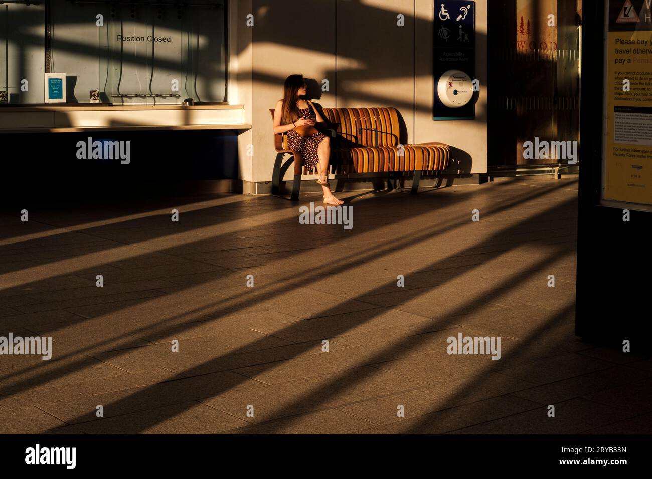 Frau, die auf einer Bank sitzt und die warme Nachmittagssonne genießt, London Bridge Station, London, UK Stockfoto