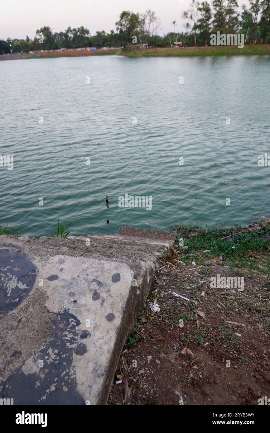 Die Stufen, die zum See führen, bestehen aus Beton mit rotem Boden um ihn herum. Von oben gesehen. Stockfoto