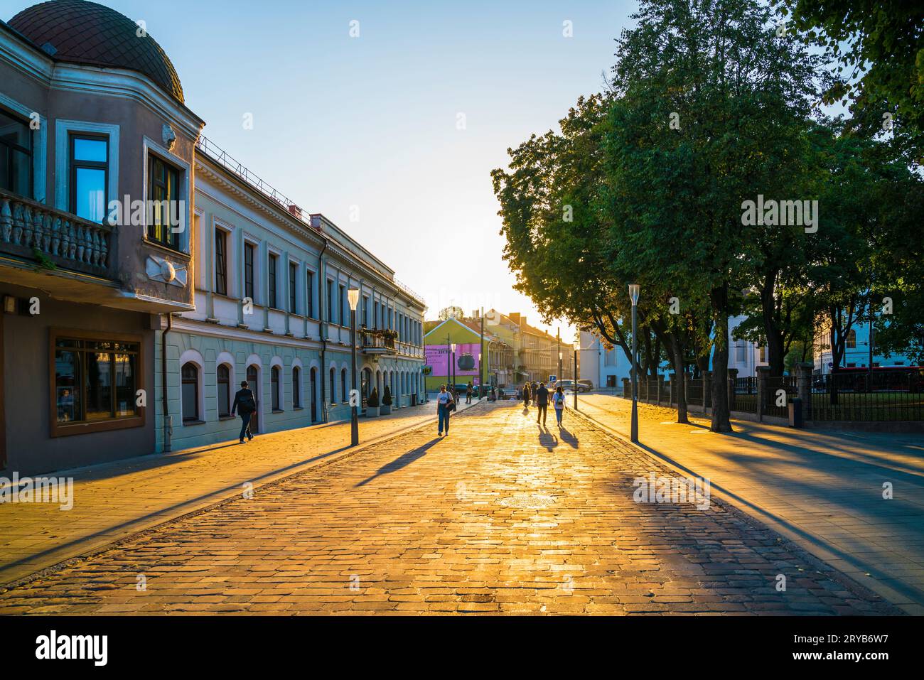 Kaunas, Litauen, 28. September 2023, Menschen spazieren durch die historische Altstadt der Stadt bei Sonnenuntergang in warmorangenem Licht im Herbst und genießen das Leben Stockfoto