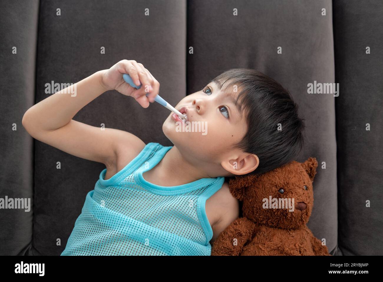 Asiatischer Junge, der seine Zähne im Wohnzimmer putzt Stockfoto