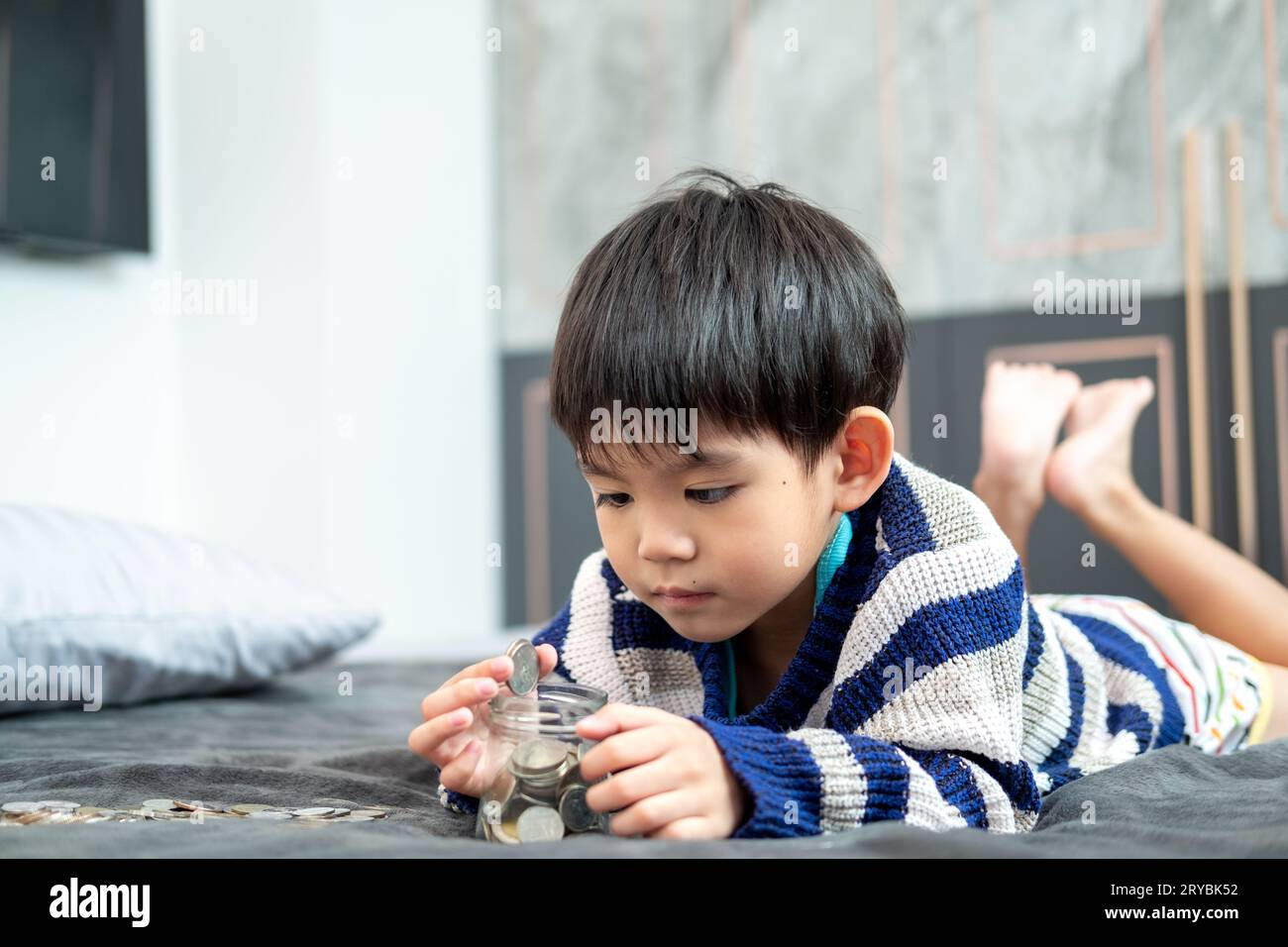 Asiatischer Junge zählt gerne Münzen, um Geld zu sparen Stockfoto