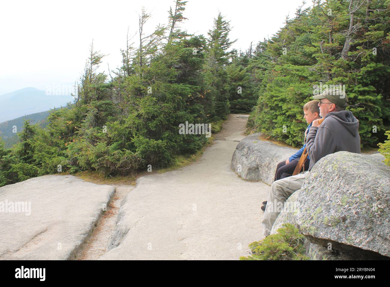 Alter Mann und Junge, die auf einem Bergweg ruhen (Wanderer, die sich ausruhen) Stockfoto