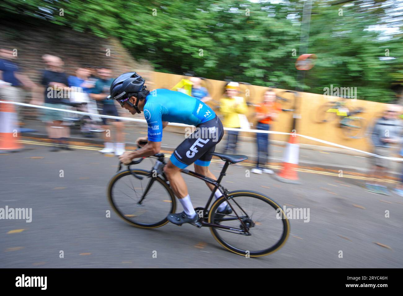 Radfahrer verschwimmen den Hintergrund, während sie die Swains Lane, Highgate, London, Großbritannien in der London Cycling Campaign Urban Hill Climb beschleunigen. Die Veranstaltung ist ein flaches Rennen auf der steilsten Straße Londons, und neben Alters- und Geschlechterkategorien gibt es Wettbewerbe für Falt- und Lastenräder. Swain’s Lane ist der berühmteste und berüchtigtste Aufstieg in London. Die Fahrspur ist ein extrem steiler Abschnitt zwischen Hampstead Heath und Highgate Cemetery mit einem Gefälle von durchschnittlich 9 % über 0,6 km, das sich aber in der Nähe der Bergspitze auf 14 % erhöht. Stockfoto