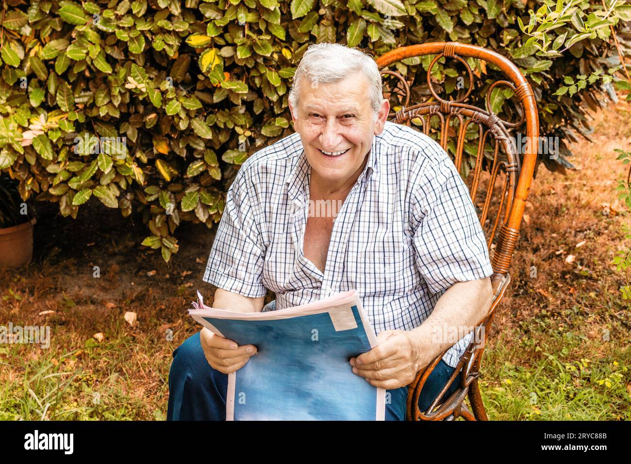 Der alte Mann liest die Zeitung im Garten Stockfoto