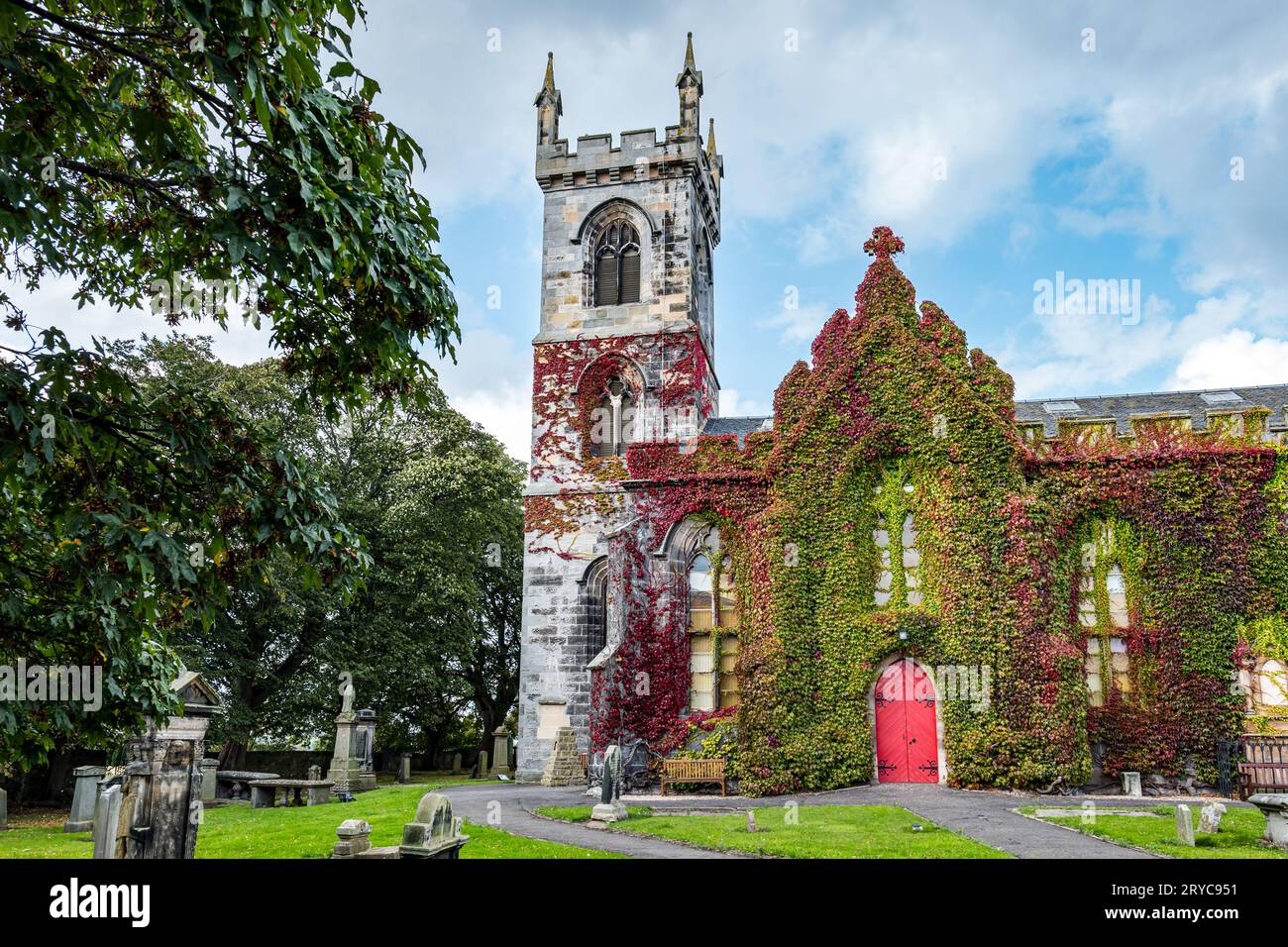 Herbstrote Efeu wächst an der Wand von Liberton Kirk oder Kirche mit roter Tür und Friedhof, Edinburgh, Schottland, Großbritannien Stockfoto