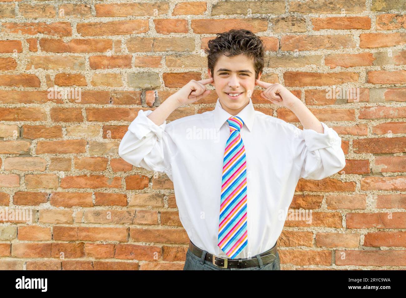 Junge, der vor einer Wand Ohren zustopft Stockfoto