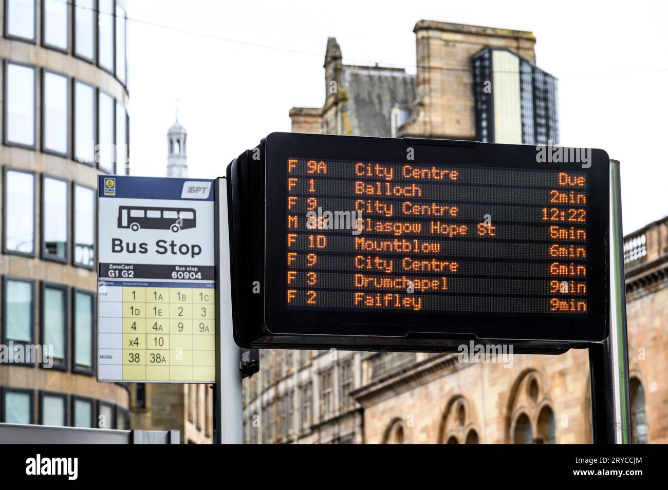 Ein LED-Echtzeit-Bushaltestellen-Schild mit einer älteren Version im Hintergrund, Glasgow, Schottland, UK Stockfoto