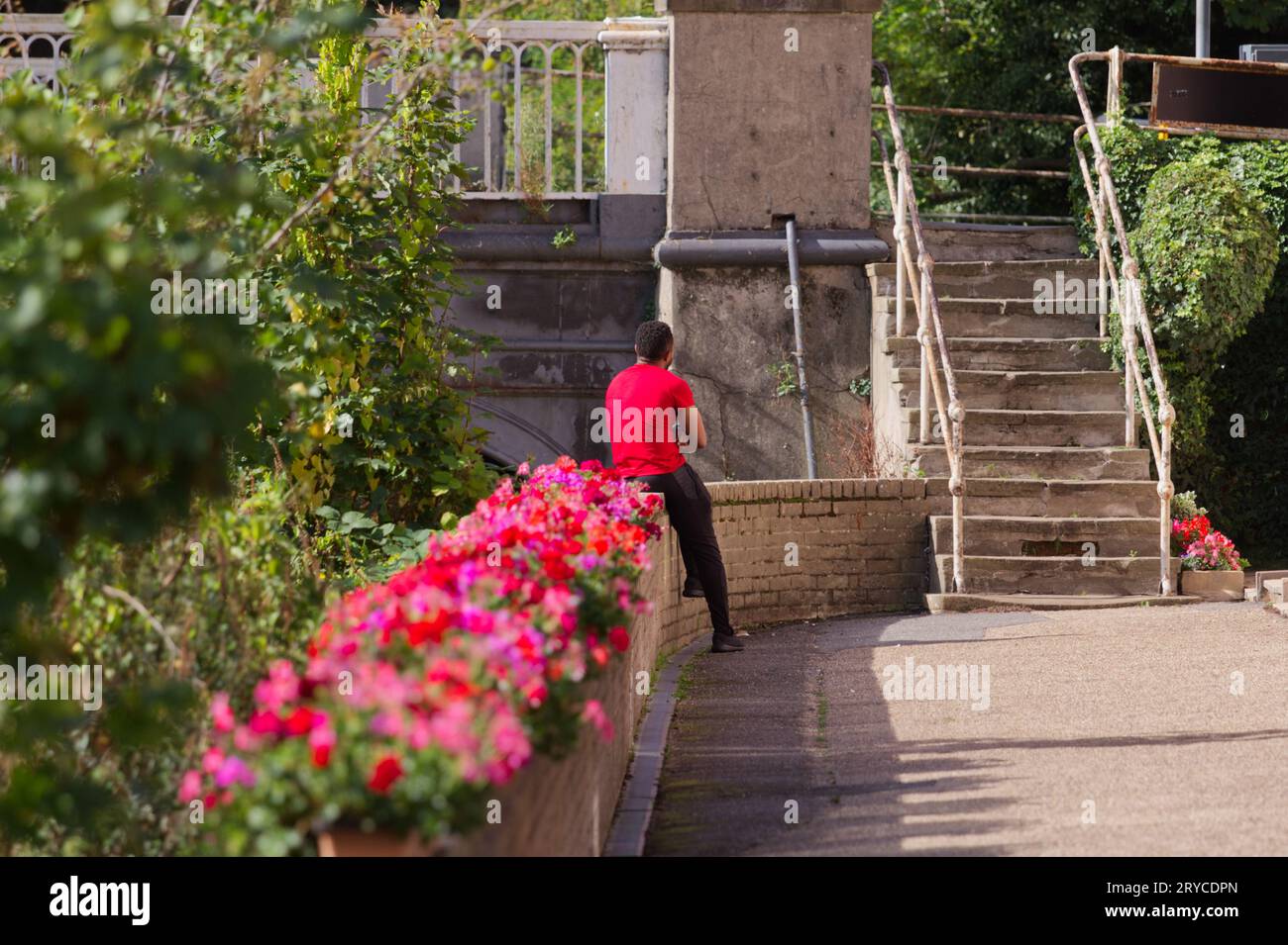 Ein Mann sitzt auf einer Mauer und wartet. Stockfoto