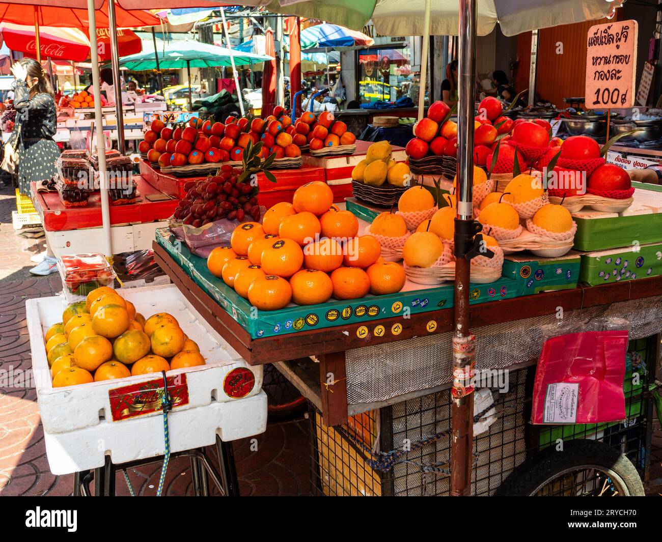 Der lebhafte Straßenmarkt in Bangkok ist mit Tischen mit köstlichen roten und orangen Früchten geschmückt. Stockfoto