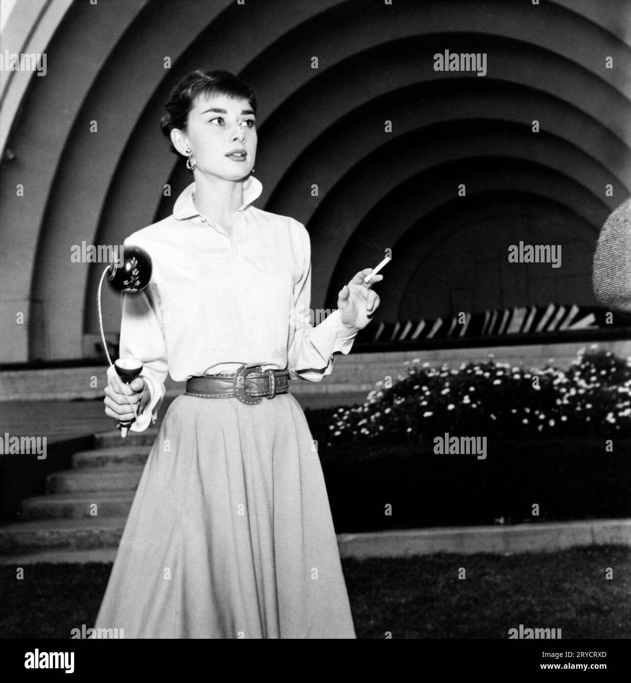 Audrey Hepburn at the Hollywood Bowl, von Earl Theisen, 1954 Audrey Hepburn at the Hollywood Bowl mit einem Spielzeug und einer Zigarette Stockfoto