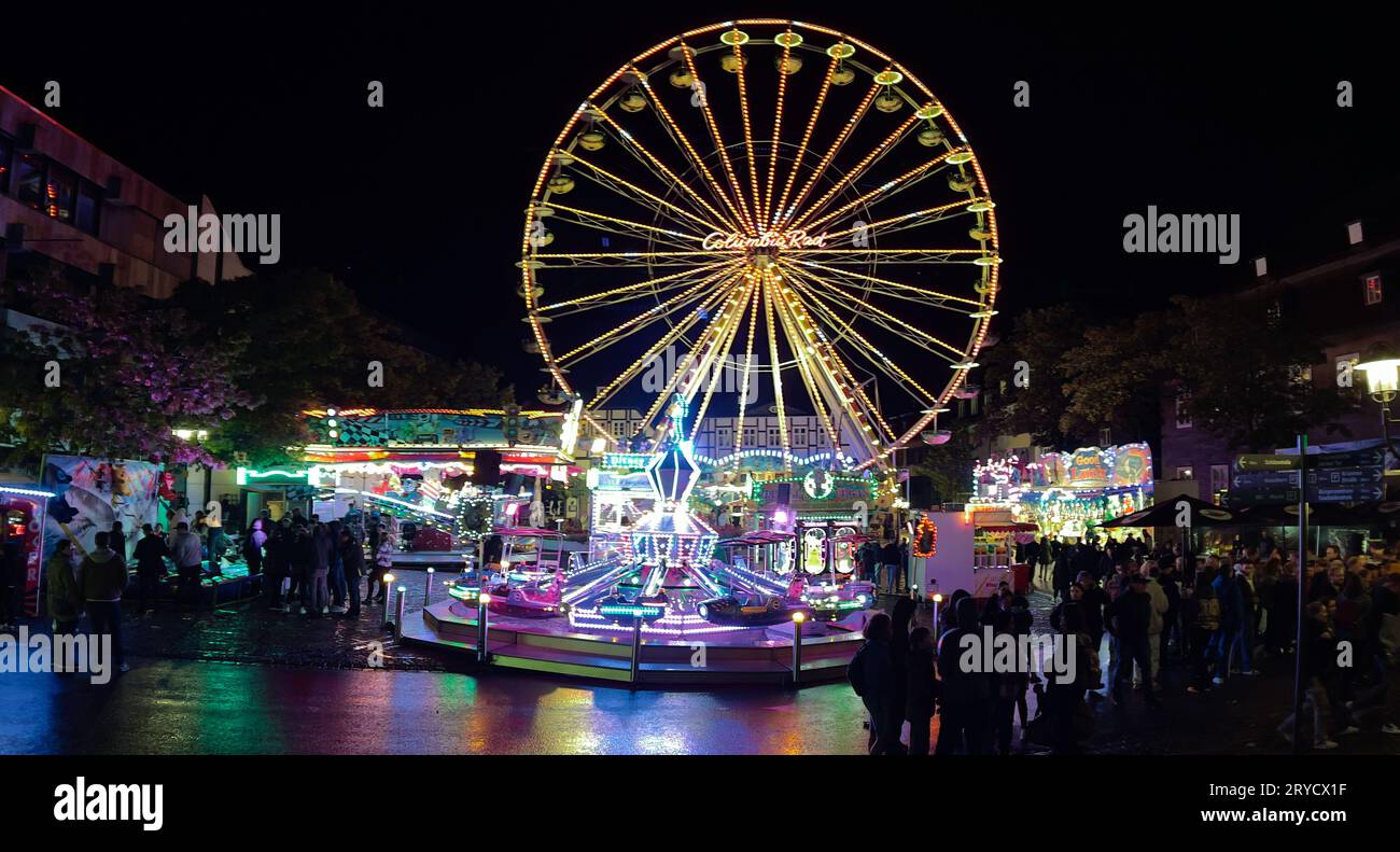 Brilon, Nordrhein-Westfalen/Deutschland - 23. September 2023: Beleuchtetes Riesenrad und Kinderkarussell am Abend auf der Brilon-Messe. Stockfoto