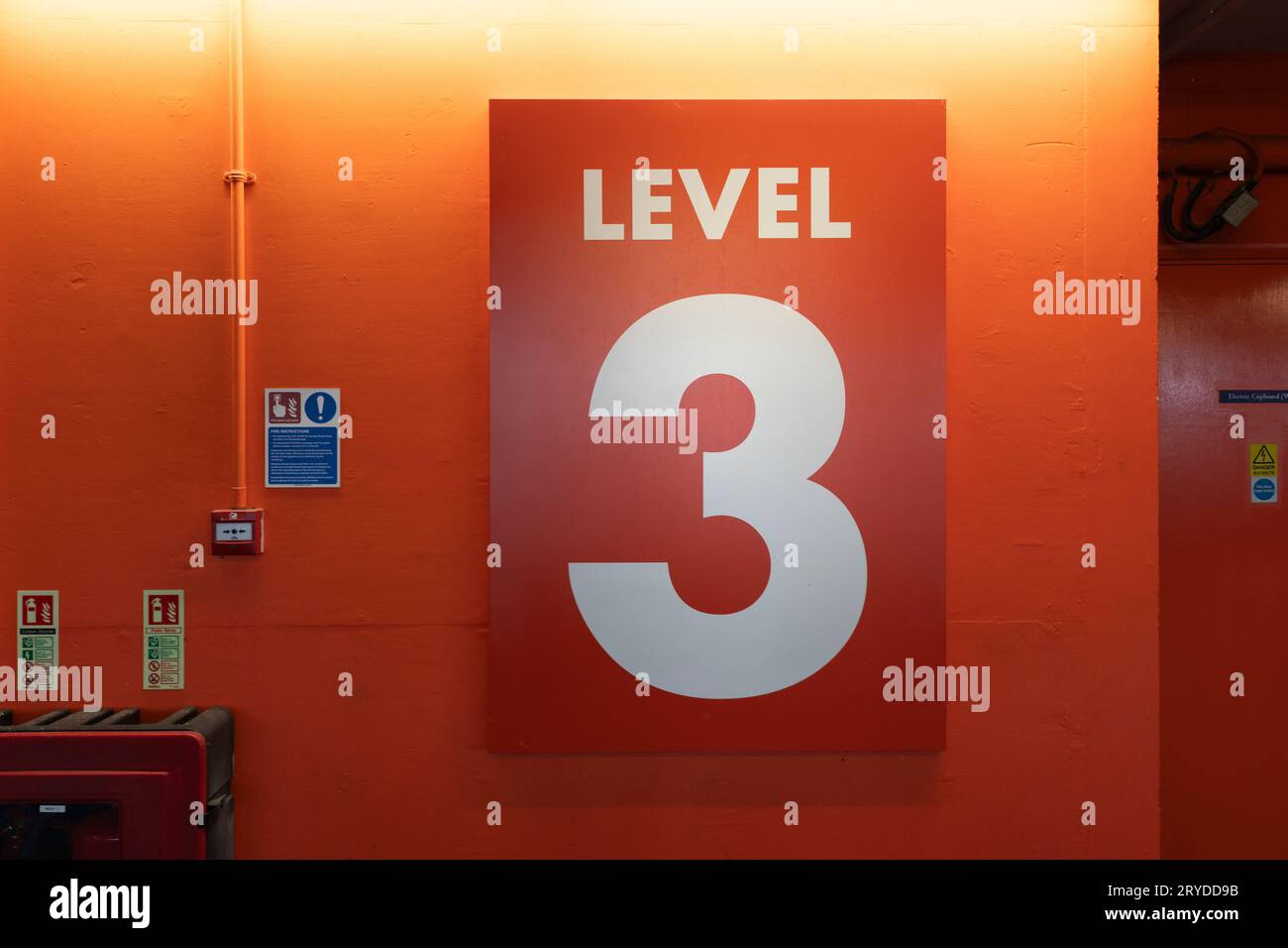 Ein riesiges rotes Schild der Stufe 3 auf dem öffentlichen Oracle Parkplatz, Reading, Großbritannien. Konzept: Ebene 3, Nummer 3, dritter Stock, dritter Parkplatz Stockfoto