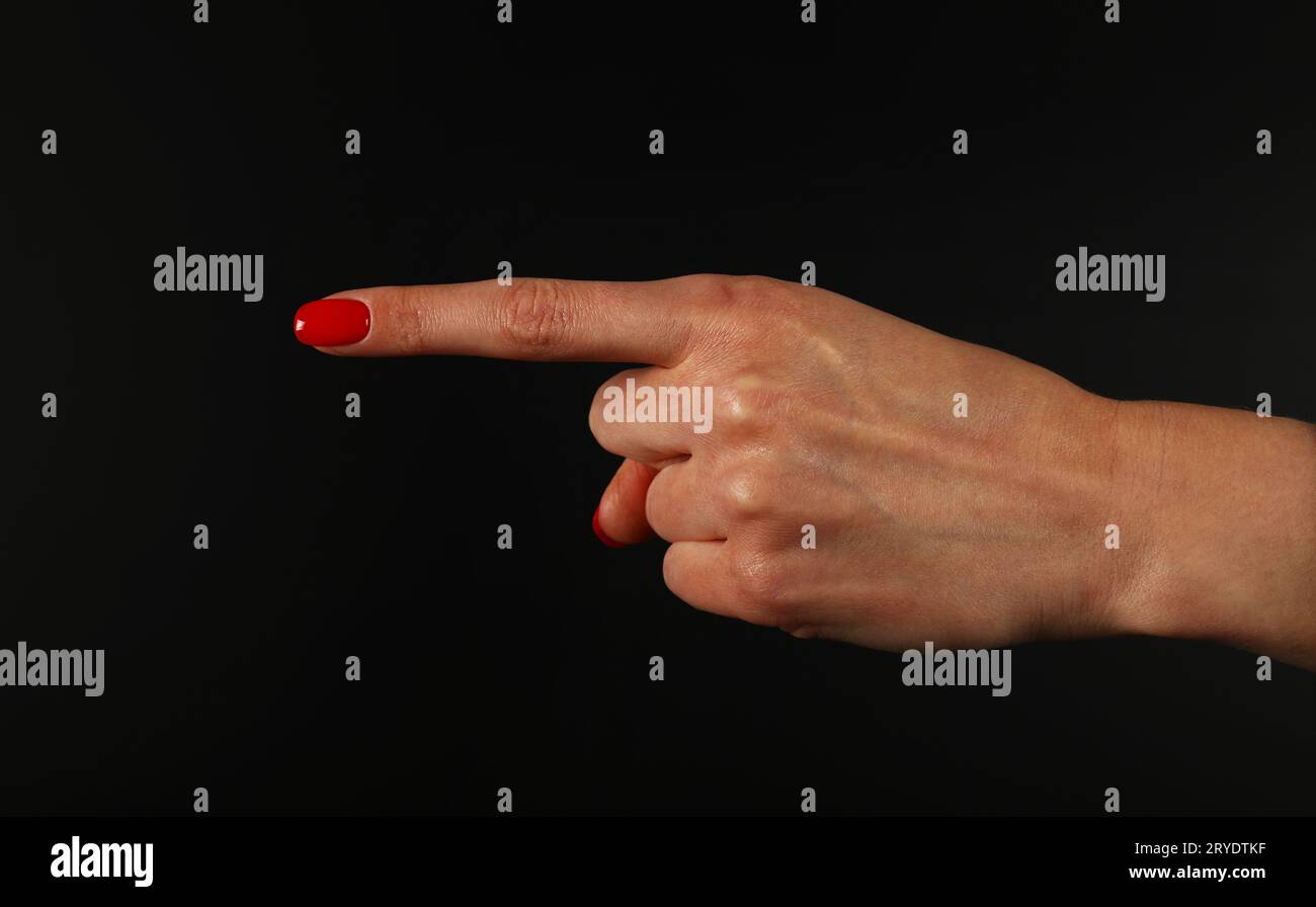 Frauenhand zeigt mit Zeigefinger über Schwarz Stockfoto