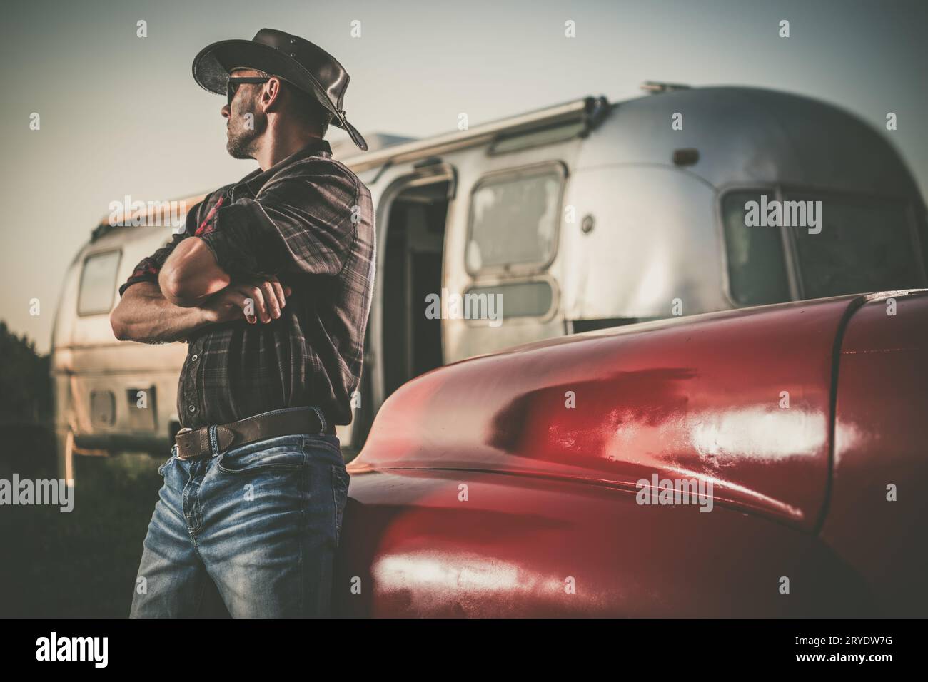 Der kaukasische amerikanische Südwest-Cowboy in seinen 40ern vor seinem Travel Trailer und Classic Pickup Truck Stockfoto