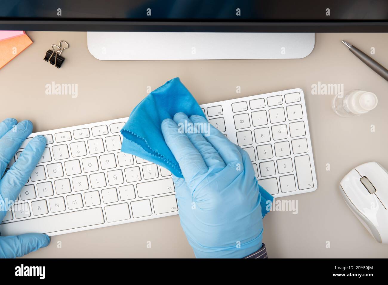 Hand mit Schutzhandschuh Reinigung einer Tastatur mit Desinfektionsmittel Stockfoto