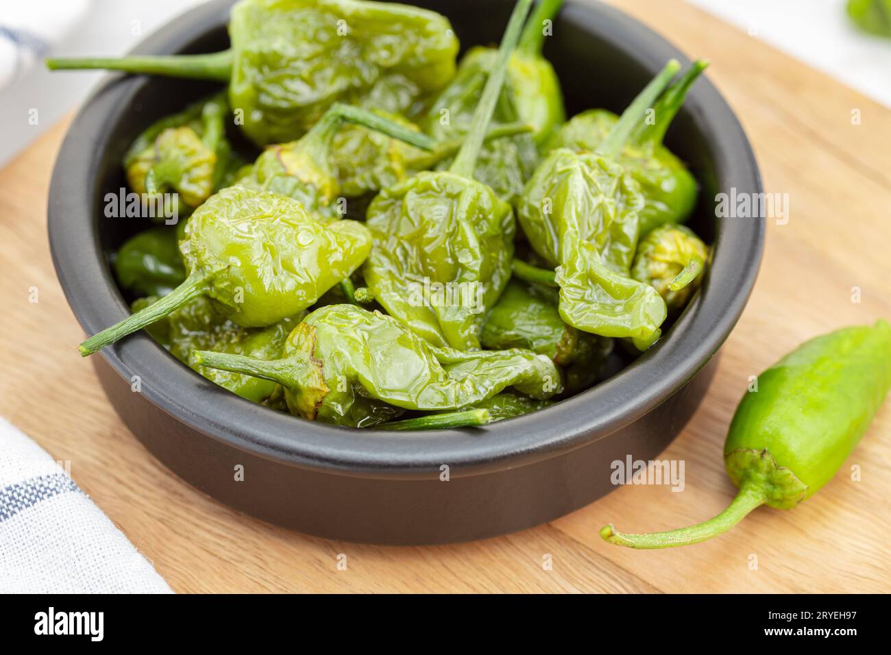 Nahaufnahme von gekochten Padron-Paprika in einer Schüssel auf Holztisch Stockfoto