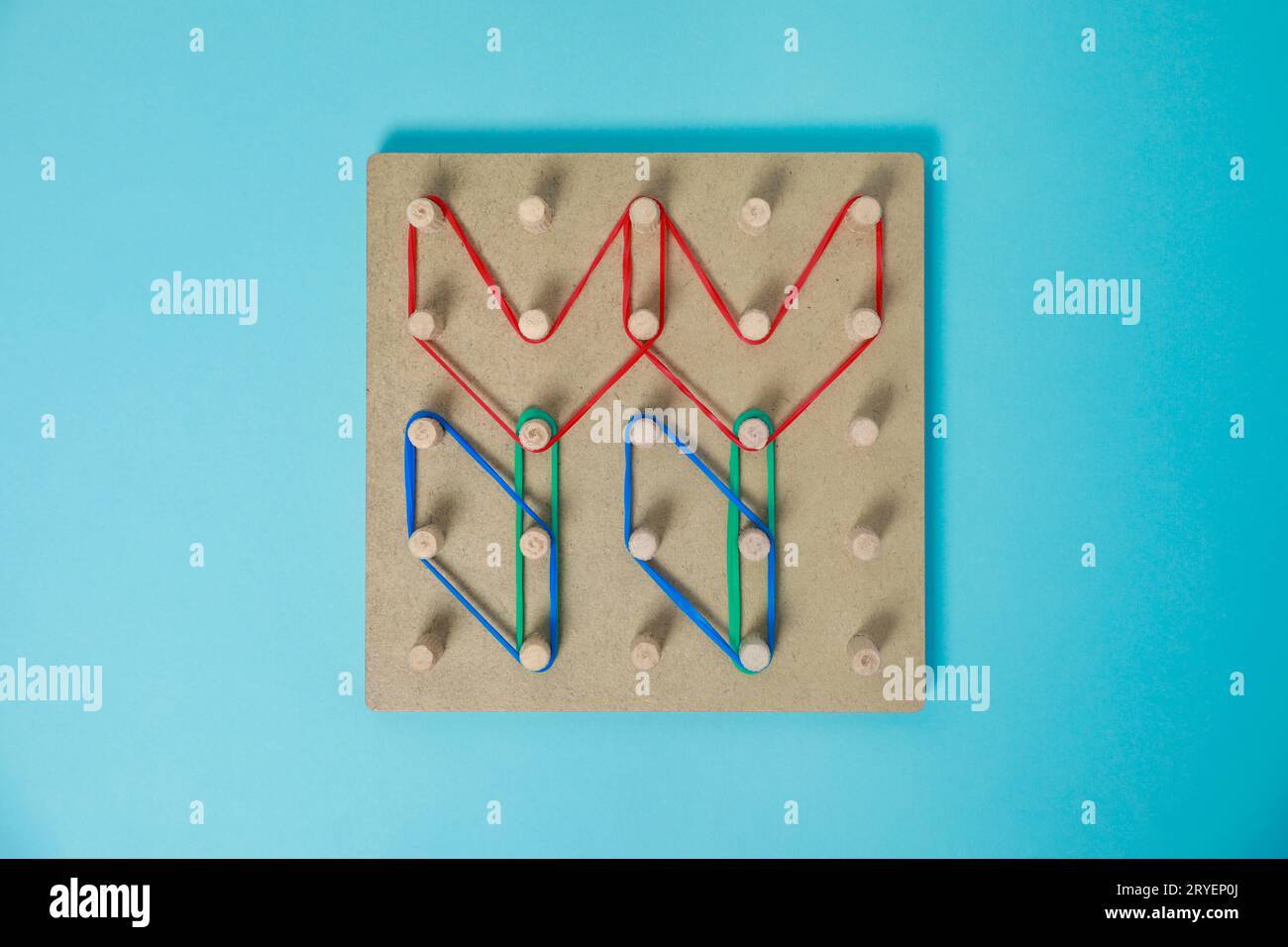 Geobord aus Holz mit Blumenformen aus Gummibändern auf hellblauem Hintergrund, Draufsicht. Lernspielzeug für die Entwicklung motorischer Fähigkeiten Stockfoto