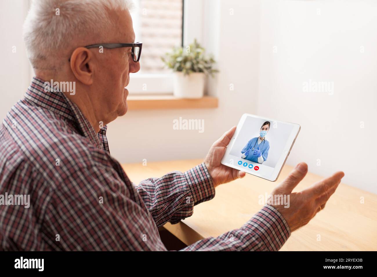 Pensionierter älterer Mann, der mit einer Ärztin des NHS über einen virtuellen telemedizinischen Videoanruf spricht Stockfoto