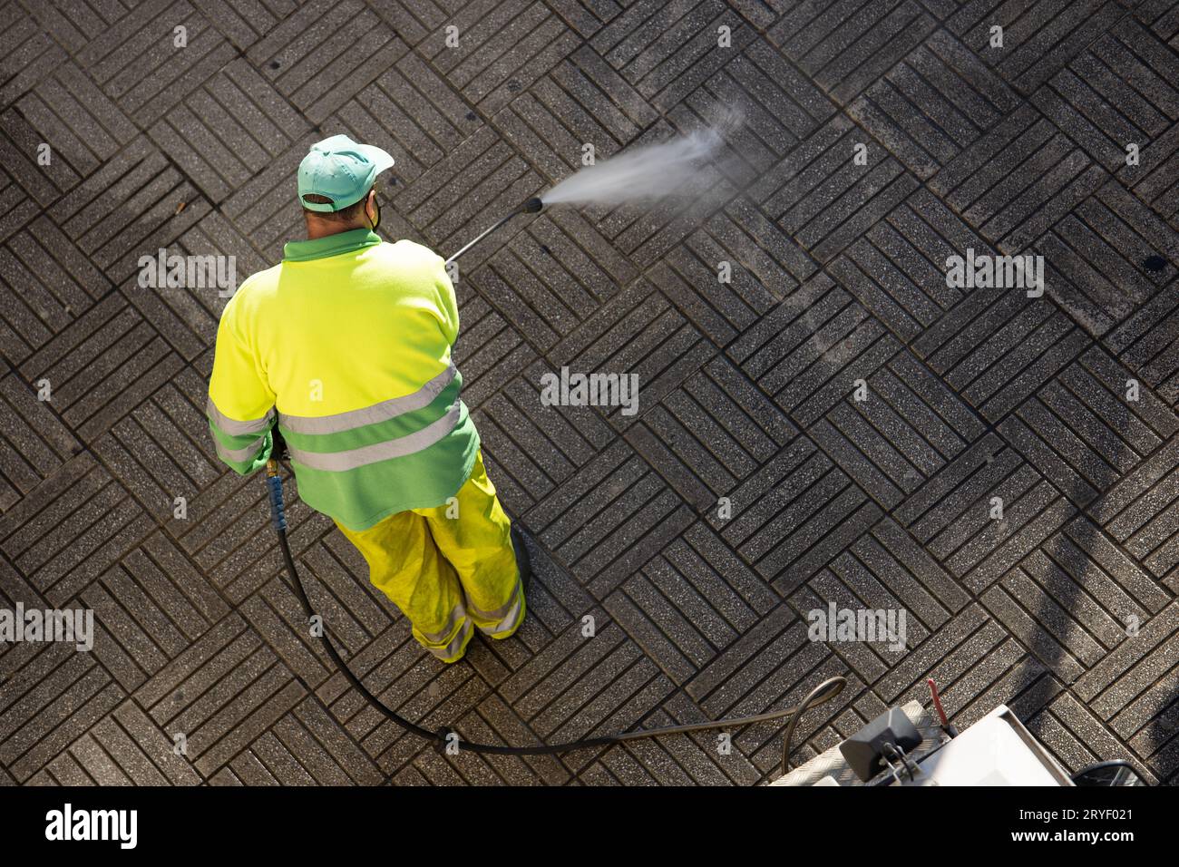 Arbeiter, die an sonnigen Tagen einen Straßenweg mit Hochdruckwasserstrahlmaschine reinigen. Speicherplatz kopieren. Draufsicht Stockfoto
