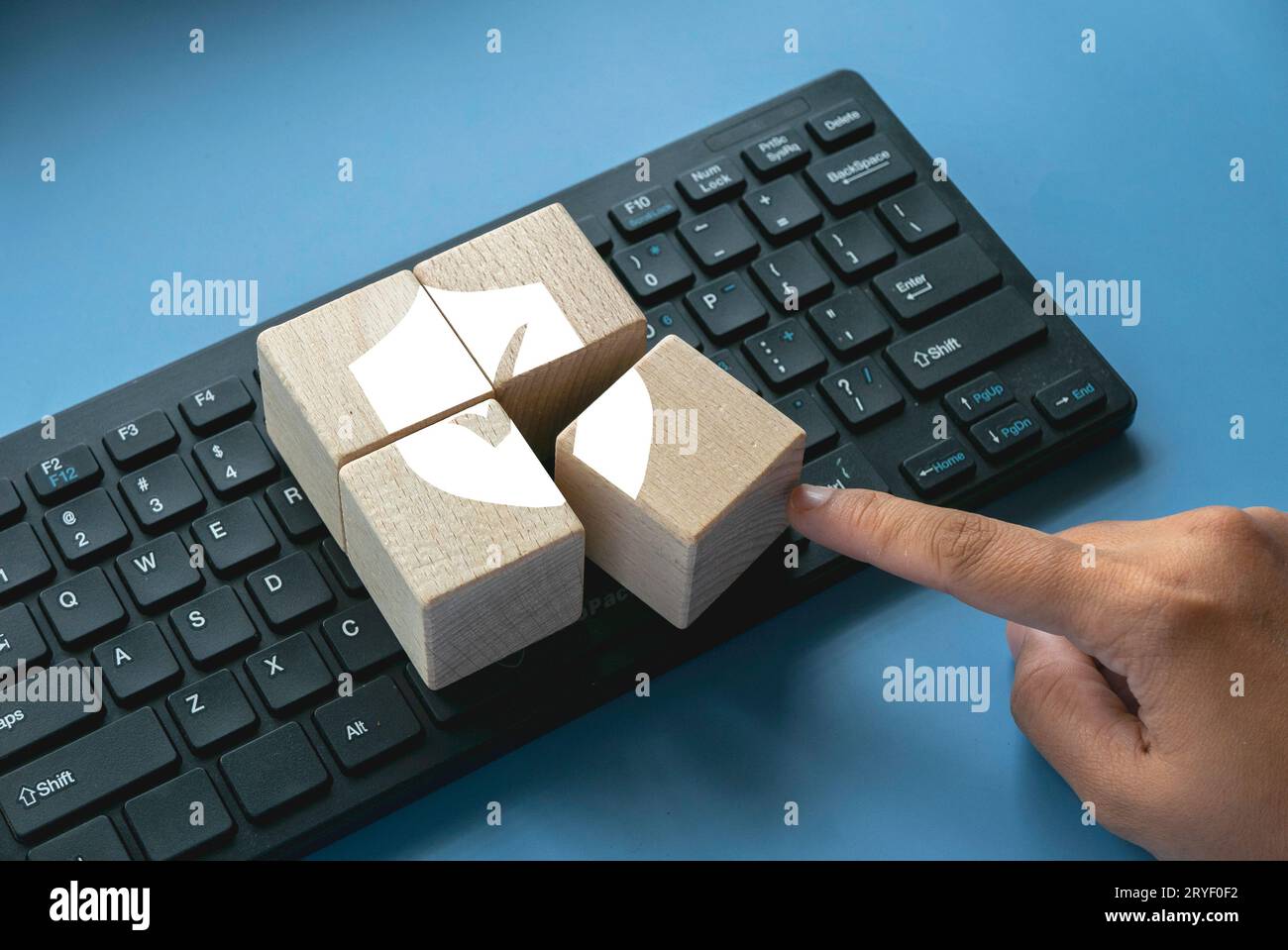 Holzwürfel mit Schild-Logo und Häkchen über einer Computertastatur. Konzept der Technologie Internet, Cyber-Sicherheit, Datenbank und Web-Schutz Conce Stockfoto