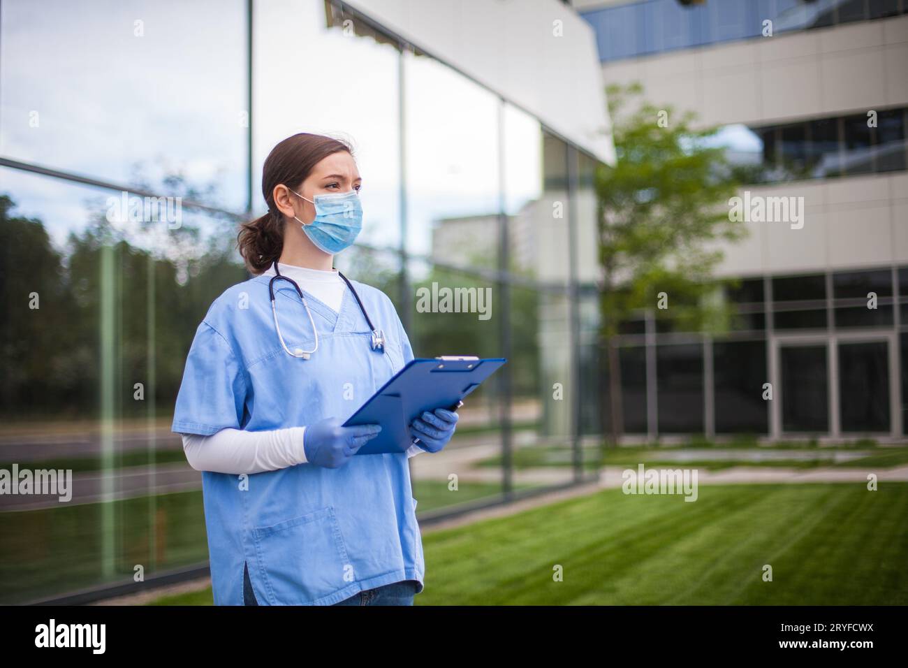 Frau Ersthelferin, die am Eingang des Krankenwagens steht und das medizinische Formular des Patienten hält Stockfoto