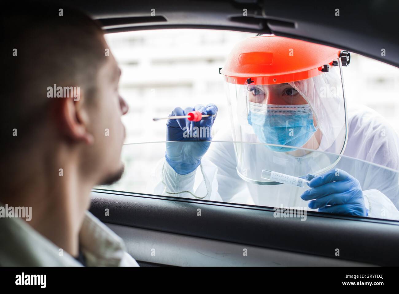 Weibliche Ärztin nimmt PCR-Tupfer-Probe von jungen männlichen Patienten Stockfoto