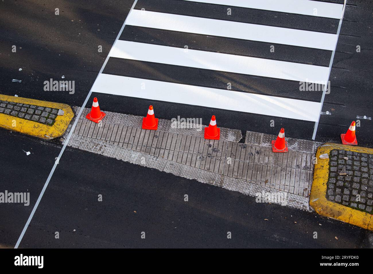 Frisch gestrichene Zebrastreifen auf einer Stadtstraße mit Kegeln und Klebeband auf dem Asphalt Stockfoto