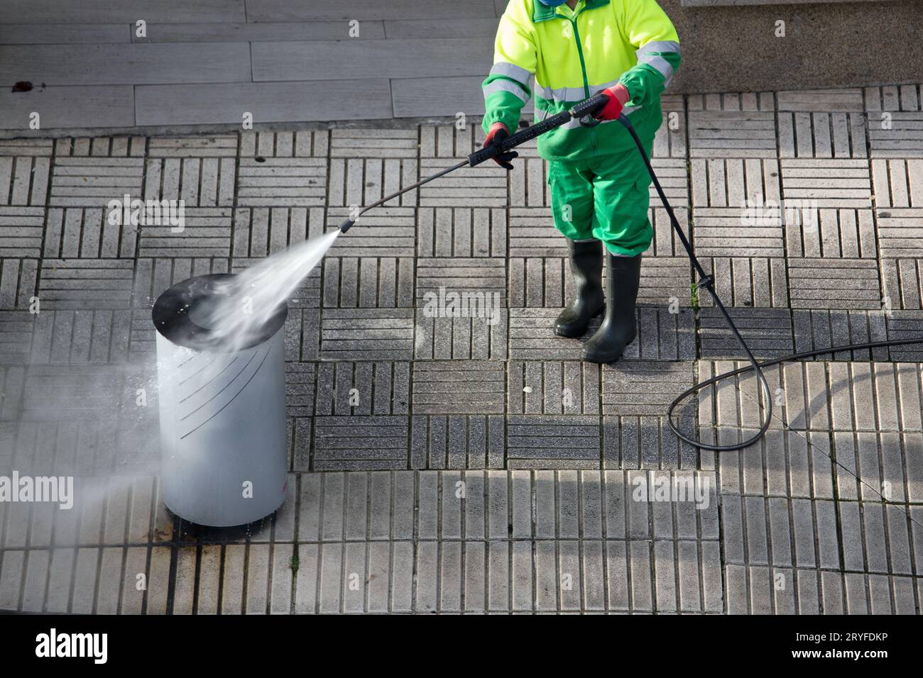 Kehrmaschine Reinigung eines Abfallbehälters auf dem Bürgersteig mit Hochdruck-Wasserstrahlmaschine. Straßenpflege Stockfoto