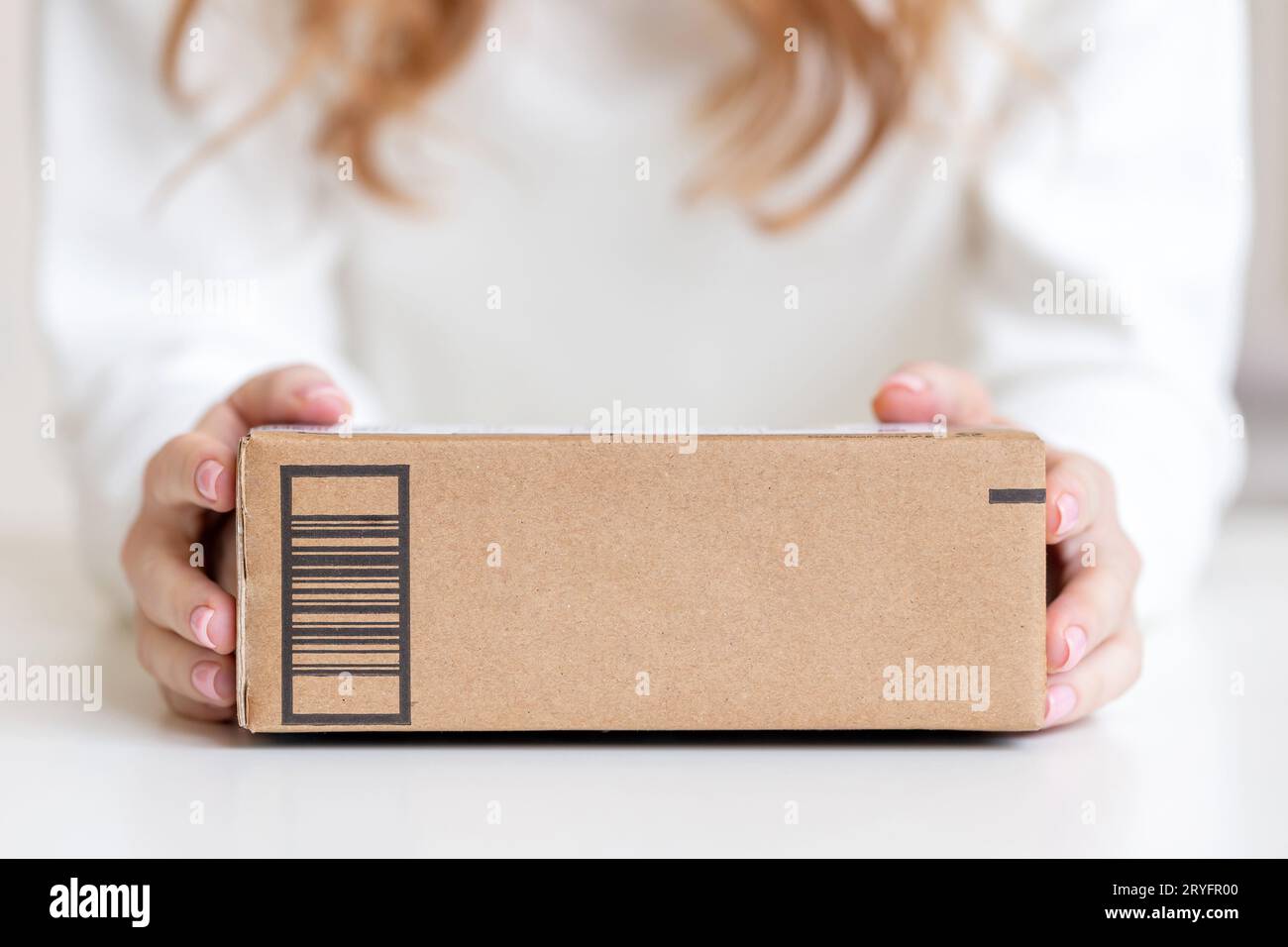 Frau in sauberem weißem Hemd, die in den Händen hält, lieferte Waren in Pappkarton. Ansprechendes Design mit Kopierraum. Stockfoto