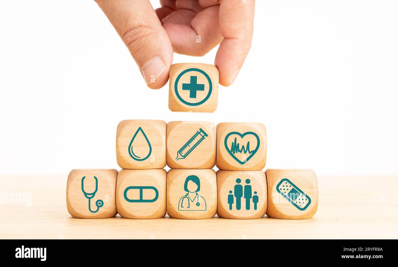 Konzept der Krankenversicherung. Holzblöcke mit medizinischen Symbolen und Hand mit einem Holzblock mit medizinischen Symbolen Stockfoto