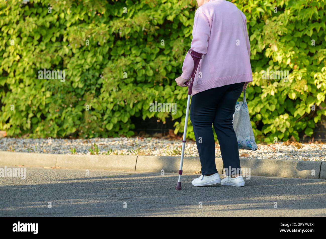 Eine alte Frau läuft mit Krücken Stockfoto