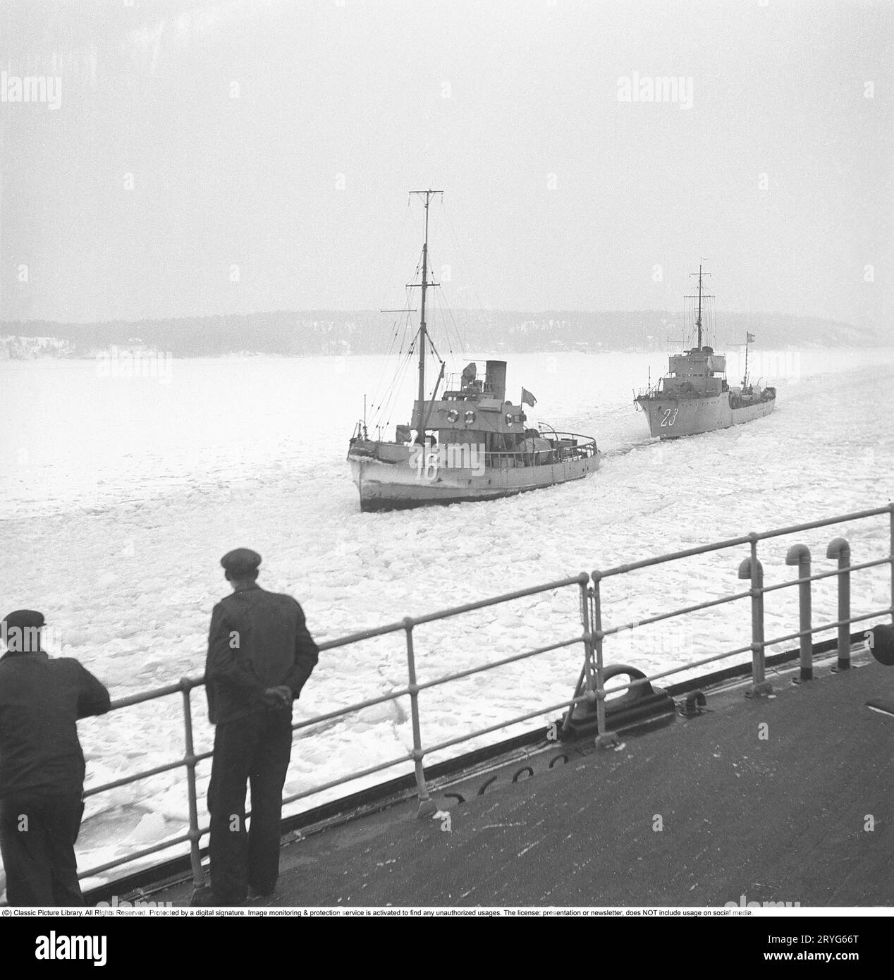 Winter auf See in den 1940er Jahren Abgebildete Besatzungsmitglieder des schwedischen Eisbrechers Ymer brechen im februar 1941 das Eis in den Binnengewässern der schwedischen Küste. Zwei Marineschiffe passieren den Eiskanal, der sich hinter dem Eisbrecher bildet. Der Eisbrecher Ymer wurde 1931-1933 in Malmö gebaut und diente 44 Jahre lang als Eisbrecher, bis er 1976 verkauft und verschrottet wurde. Die Winter während des Zweiten Weltkriegs waren oft außergewöhnlich kalt und das Eis wurde zu einem großen Problem für die Schifffahrt und das Militär. Ymer war der erste große Meereisbrecher, der einen Dieselantrieb verwendete Stockfoto