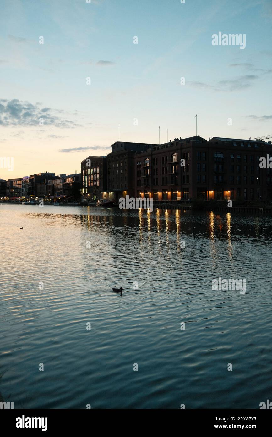 Vertikale Aufnahme eines alten Backsteingebäudes, das bei Sonnenuntergang im Hafen von Munster beleuchtet wird Stockfoto