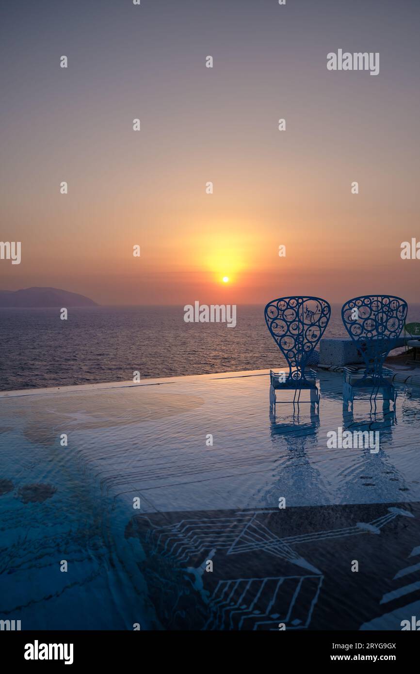 IOS, Griechenland - 8. September 2023 : Blick auf zwei dekorierte Stühle in einem Swimmingpool mit Blick auf die Ägäis und einen wunderschönen Sonnenuntergang in iOS Griechenland Stockfoto