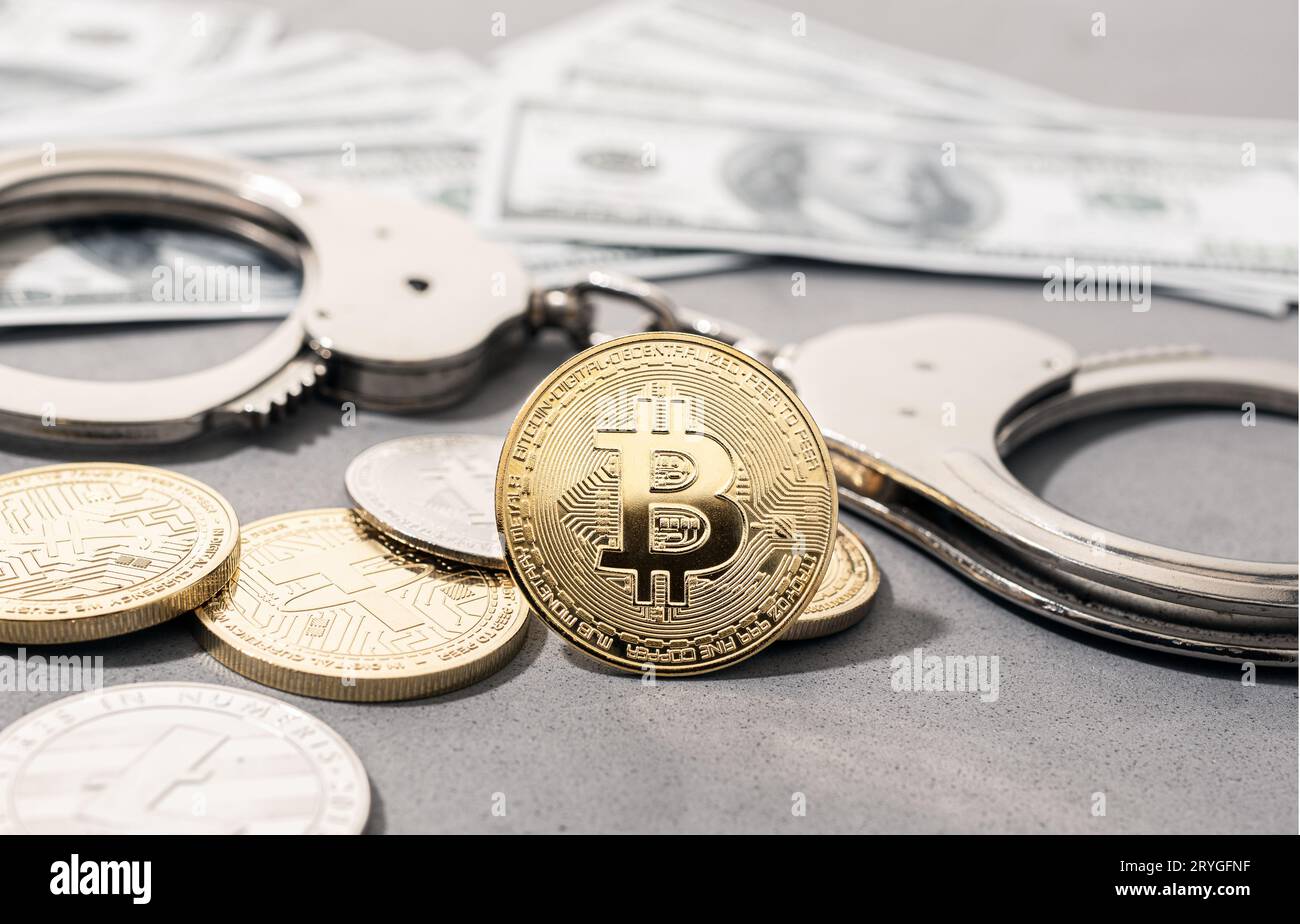Konzept für Betrug bei Kryptokriminalität. Bitcoin- und Krypto-Münzen, Handschellen und US-Dollar-Banknoten Stockfoto