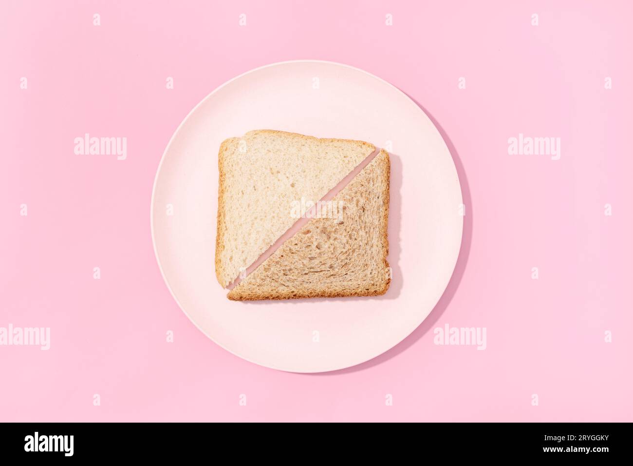 Weißes und Vollkorn-Sandwich-Brot auf einem Teller mit rosafarbenem Hintergrund. Flach verlegt Stockfoto