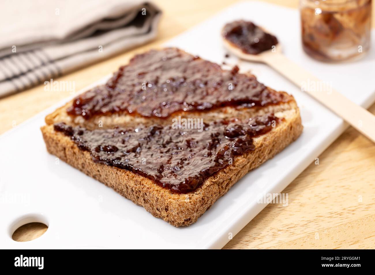 Nahaufnahme von Vollkornbrot-Toast-Sandwich und Himbeer-Bio-Marmelade auf Holztisch Stockfoto