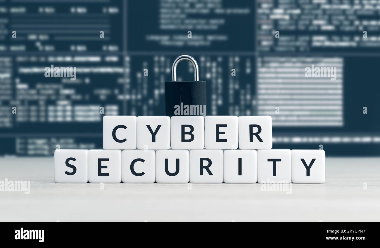 Cyber-Sicherheitsworte auf Blöcken, geschlossenes Vorhängeschloss und Bildschirm mit Computerdaten im Hintergrund Stockfoto